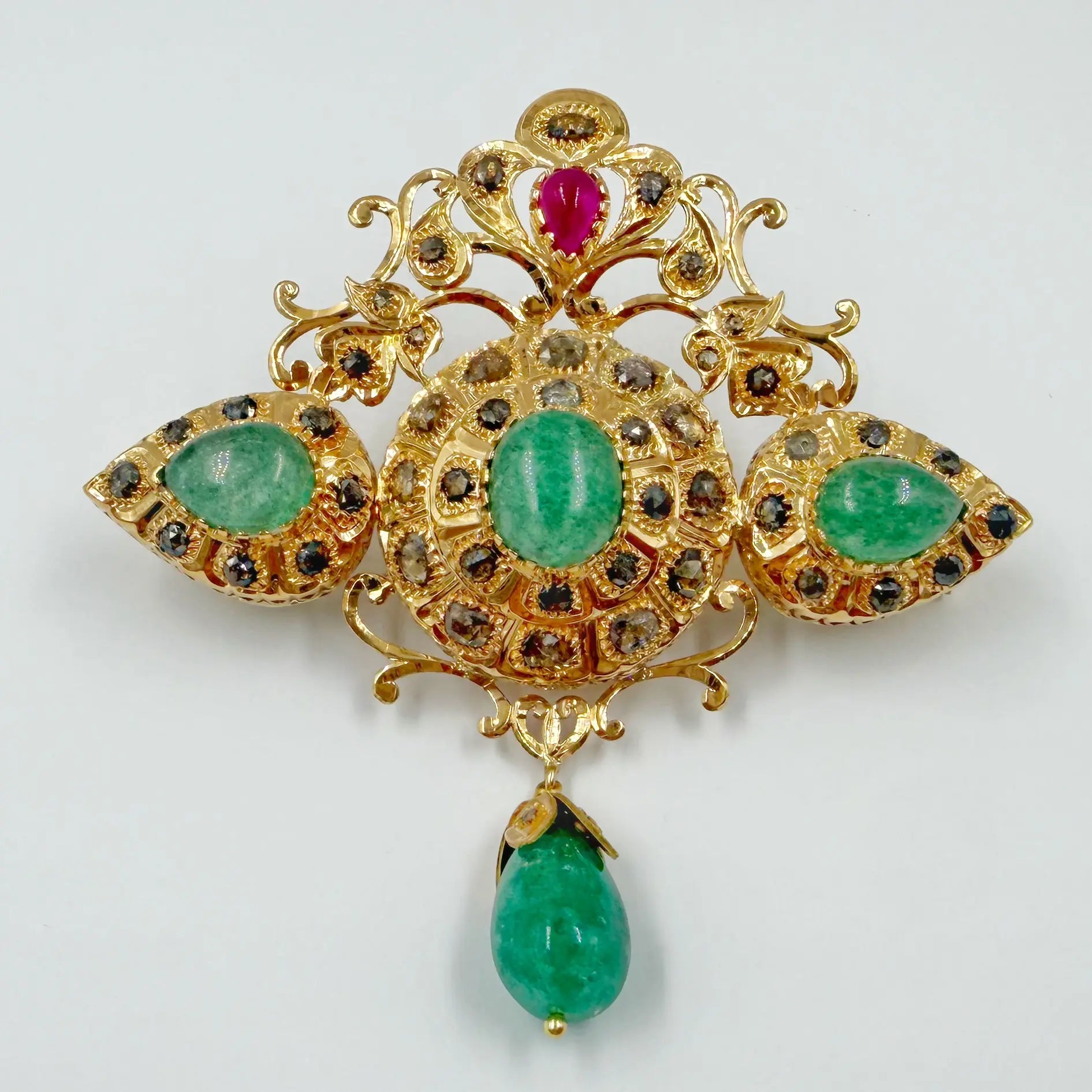 Broche traditionnelle en or rose sertie de rosaces, pierres vertes et pierre rouge